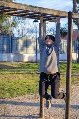 Paralel çubukları olan bir parkta egzersiz yapan genç