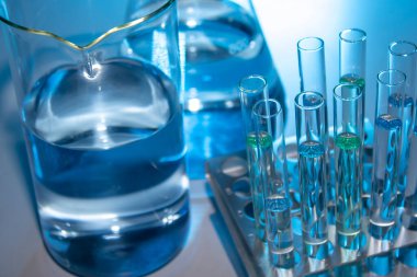 Beher, matara, mezun olmuş silindirler ve test tüpleri gibi laboratuvar malzemelerini kapatın.