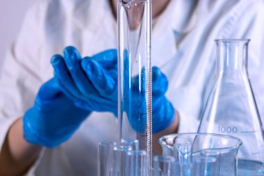 Bir bilim adamının eli pipetle örnek alıyor.