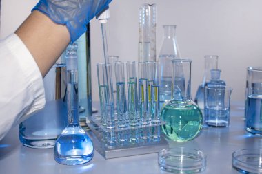 Bir bilim adamının eli pipetle örnek alıyor.