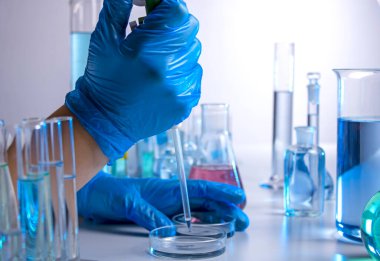 Bir bilim adamının eli pipetle örnek alıyor.