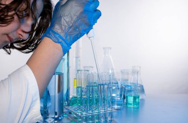 Genç bilim adamı bir laboratuarda pipetle örnek alıyor.