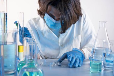 Genç bilim adamı bir laboratuarda pipetle örnek alıyor.