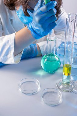 Genç bilim adamı bir laboratuarda pipetle örnek alıyor.