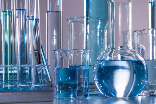 Beher, matara, mezun olmuş silindirler ve test tüpleri gibi laboratuvar malzemelerini kapatın.