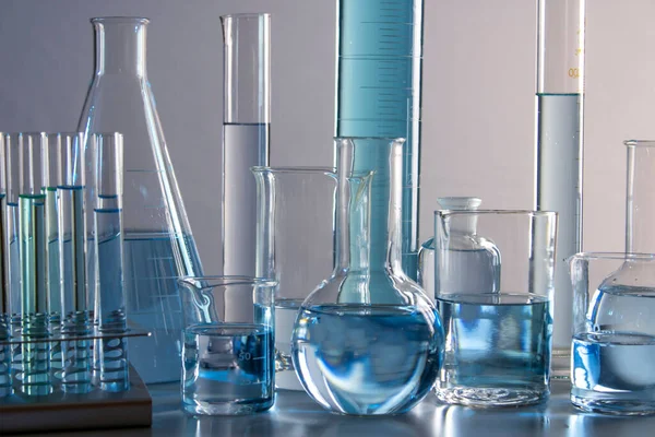 Beher, matara, mezun olmuş silindirler ve test tüpleri gibi laboratuvar malzemelerini kapatın.