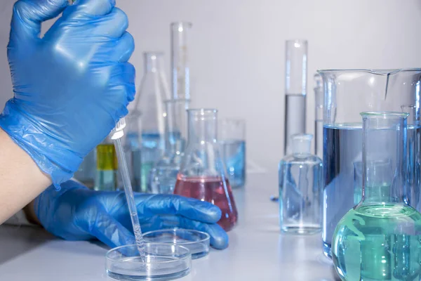 Bir bilim adamının eli pipetle örnek alıyor.