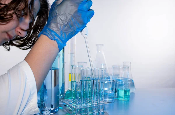 Genç bilim adamı bir laboratuarda pipetle örnek alıyor.