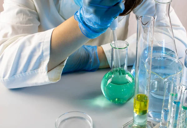 Genç bilim adamı bir laboratuarda pipetle örnek alıyor.