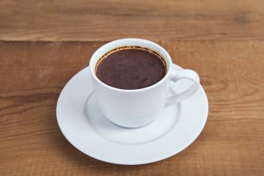 Ahşap bir masa arkasında bir fincan sıcak kahve. Türk kahvesi.