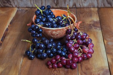 Tahta arka planda izole edilmiş taze, sulu kırmızı ve siyah üzümler..