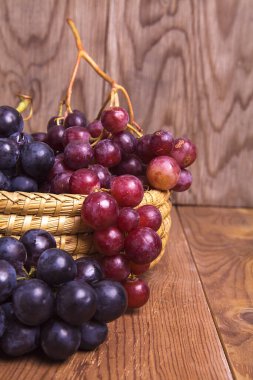 Tahta arka planda izole edilmiş taze, sulu kırmızı ve siyah üzümler..