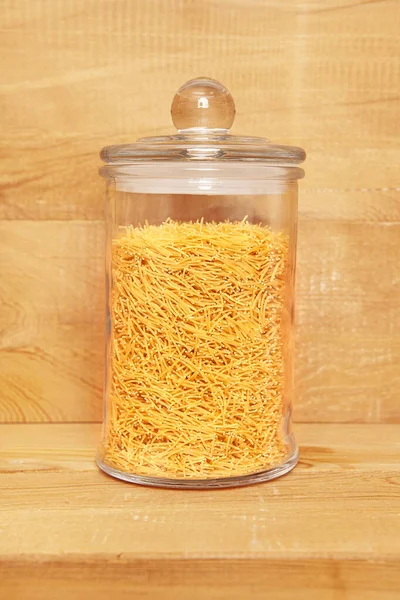 Ahşap arka planda cam kavanozda pişmemiş vermicelli..