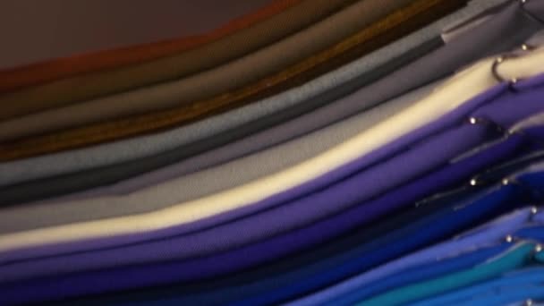 Pilha de roupas dobradas brilhantes de várias cores. — Vídeo de Stock