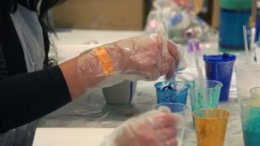 Yakın plan el, tek kullanımlık plastik bardakta mavi suyu karıştırıyor..
