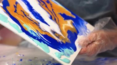 Sanatçı tuvale akrilik boya döküyor..