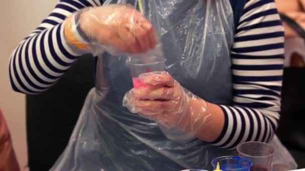एक प्लास्टिक कप में रंगों को हिलाते हुए बंद-अप हाथ . — स्टॉक वीडियो