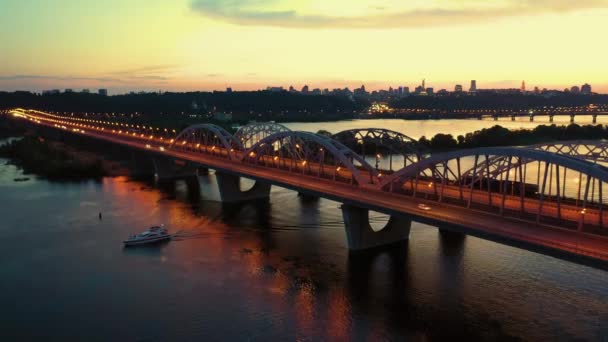 Освещённый мост над рекой с отражающими огнями в воде. — стоковое видео