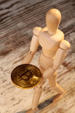 Yakın plan ahşap manken altın bitcoin tutar..