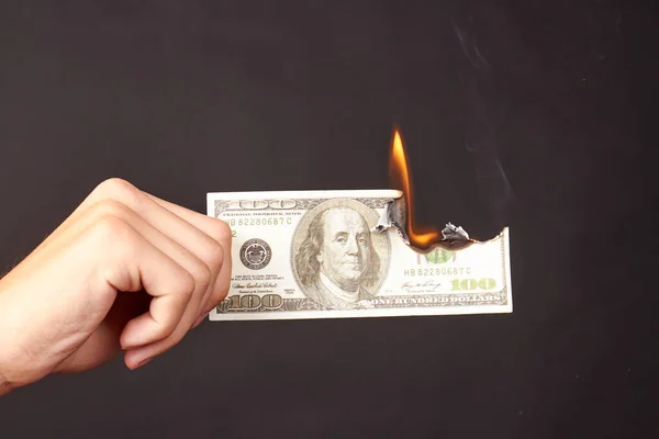Ruka drží hořící dolar izolované na černém pozadí. — Stock fotografie