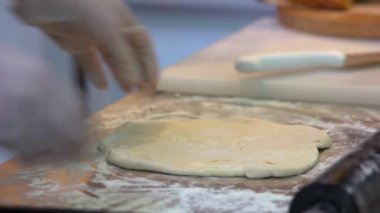 Yakın plan aşçı elleri yoğurtlanmış hamur katlıyor..