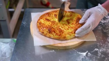 Yakın çekim fırıncılar elleri pizza dilimlemek için tekerlek dilimleyicisini kullanıyorlar..