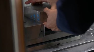 İşçi bir çilingir mengenesine metal blok yüklüyor.