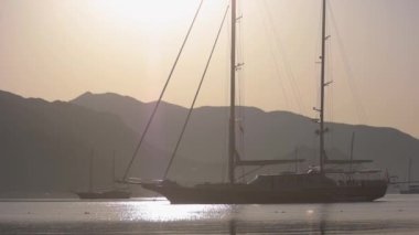 Yelkenli, dağların arka planında yol alıyor..