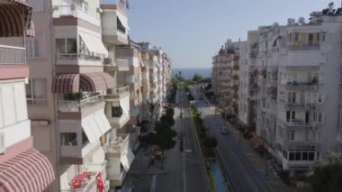 Şehir caddesinin arka planında yerleşim binaları ve deniz olan hava manzarası..