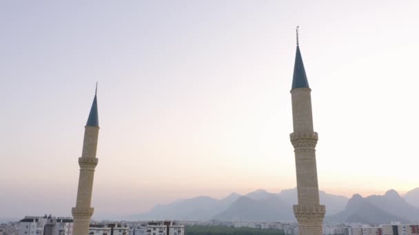해질 녘 하늘을 향한 두 개의 첨탑 이 있는 모스크. 뒤에 보이는 산의 실루엣. — 비디오