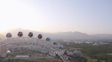 Şehir manzarasının arka planında lunaparkta dönme dolap.