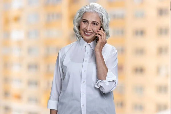 Счастливая старшая деловая женщина разговаривает по мобильному телефону. — стоковое фото