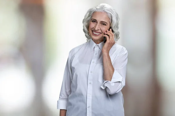 Portrait of cheerful mature business lady talking on mobile phone. — Stock Photo, Image