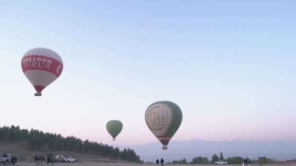 Tres globos de aire caliente de colores se elevan lentamente al cielo de la mañana con montañas en el fondo. — Vídeos de Stock