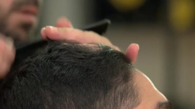 Close up man is getting haircut by hairstylist at barbershop salon.