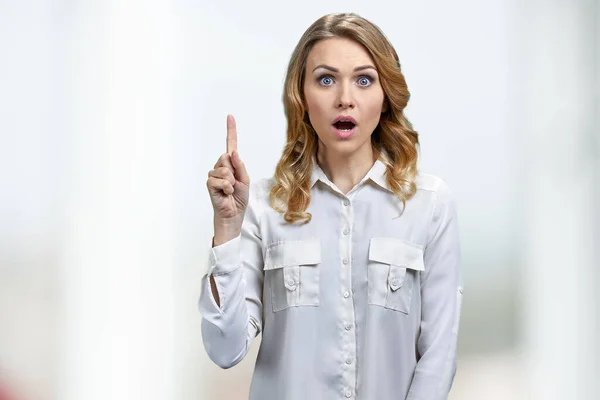 Junge energische Frau zeigt mit erhobenem Finger auf weißem Hintergrund. — Stockfoto