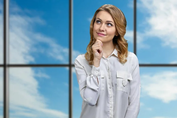 Beautiful smiling young woman daydreaming with hand on chin gesture. — Stock Photo, Image