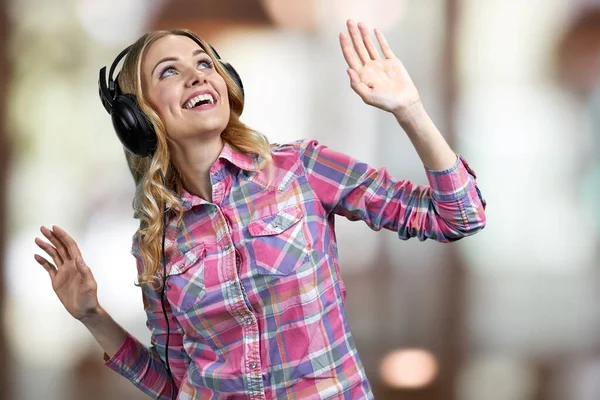 Fröhliche junge Frau mit Kopfhörern, die drinnen Musik hört. — Stockfoto