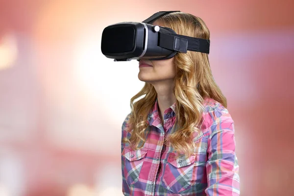 Ragazza caucasica utilizzando cuffia realtà virtuale su sfondo rosso sfocato. — Foto Stock