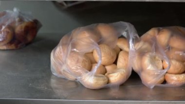 Yuvarlak ekmek çörekleri plastik poşetlerde fırın tepsisinde.