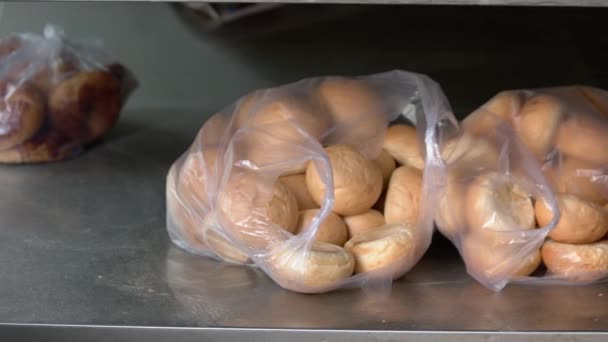 Ronde broodbroodbroodjes in plastic zakken op bakplaat in de bakkerij. — Stockvideo