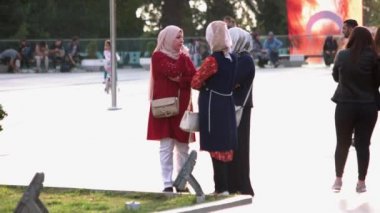 Geleneksel türbanlı üç Müslüman kadın açık havada konuşuyor..