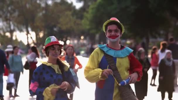 Mannelijke en vrouwelijke clowns wandelen op straat op een zomerdag. — Stockvideo