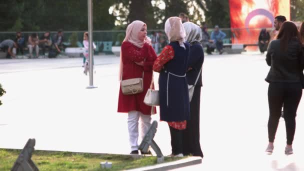 Drie moslimvrouwen in traditionele hijab hoofddoeken praten buiten. — Stockvideo