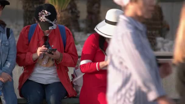 Két nő használja a telefonját, miközben a szabadban ülnek.. — Stock videók