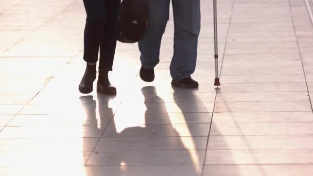 Uomo anziano con il bastone da passeggio aiutato da una donna più giovane in strada. — Video Stock
