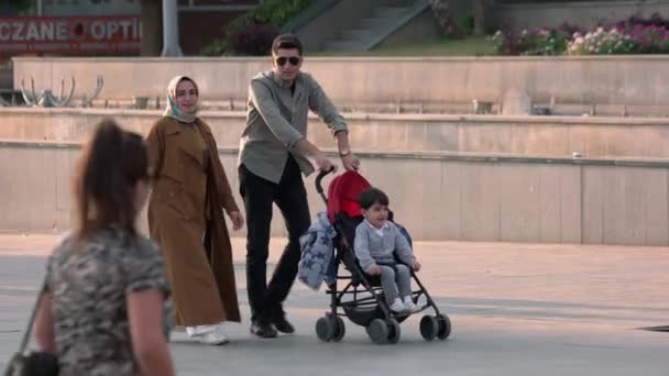 Junge muslimische Familie läuft mit Kinderwagen über den Stadtplatz. — Stockvideo
