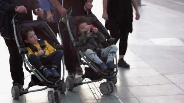 Zwei befreundete Familien mit Kinderwagen laufen auf der Stadtstraße. — Stockvideo