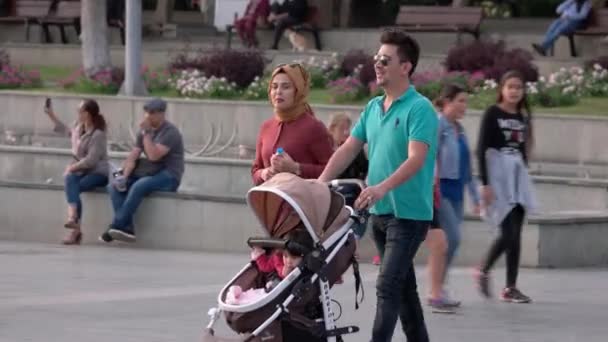 赤ちゃんを持つ若いイスラム教徒の観光客街の広場を歩くベビーカー. — ストック動画