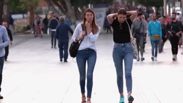 Dos hermosas mujeres jóvenes caminan por la calle de la hermosa ciudad europea. — Vídeo de stock